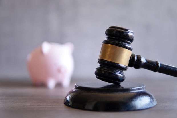 Closeup image of judge gavel and piggy bank. 