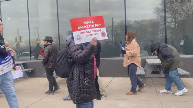 Workers hold signs that say Make Amazon Pay in front of Whole Foods 