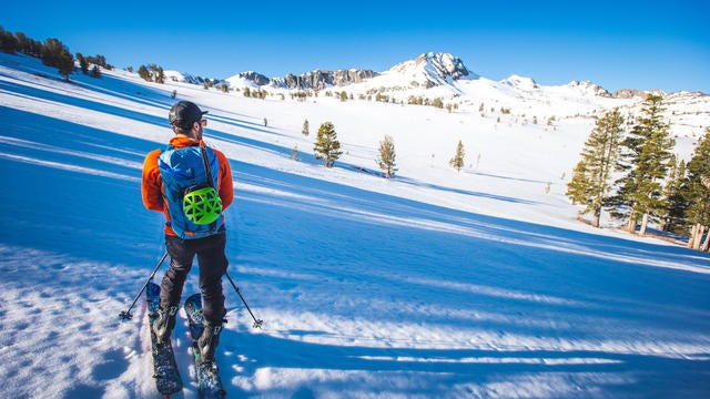 Man backcountry skiing with snowy mountain in the background 