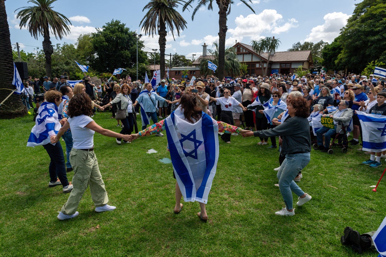 Protesters hold signs and wave Israeli flags as others dance 
