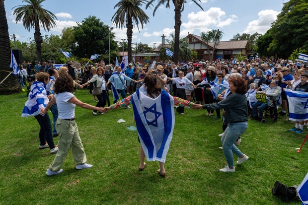 Protesters hold signs and wave Israeli flags as others dance 
