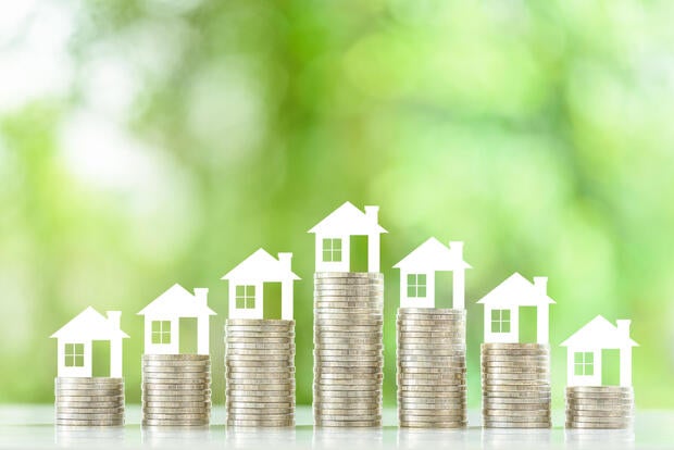 Mortgage loan or home equity loan, financial concept : Tiny model residential house perched atop coin stacks, depicting home loan or borrowing money to purchase a new home for first time homebuyer. 