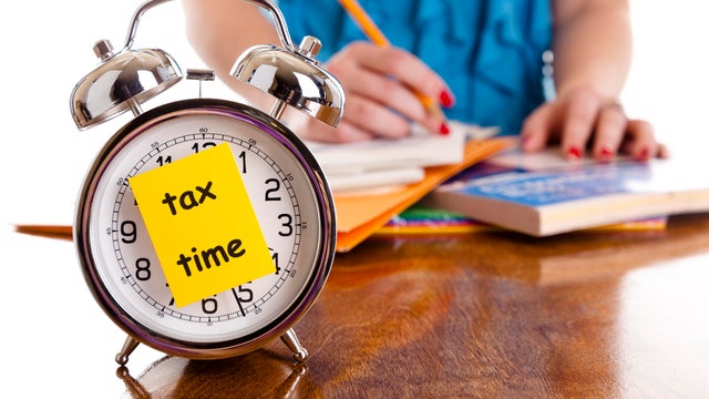 Time:  Alarm clock, income tax time note.  Woman background. Reminder. 
