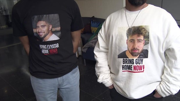 One man wears a shirt that says "bring Evyatar home now!" under a photo of a man, and another man wears a shirt that says "bring Guy home now!" under a photo of a man. 