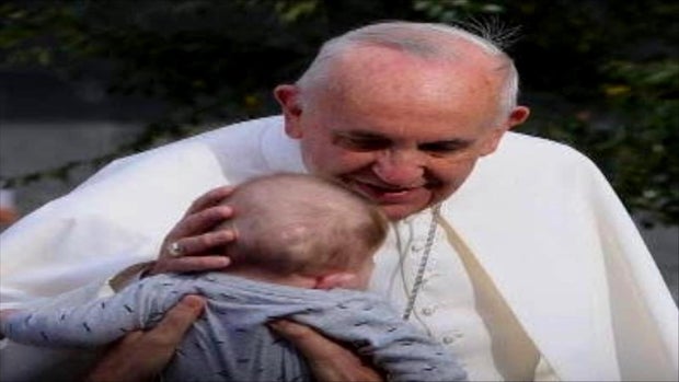Pope Francis touches the head of a baby 