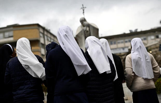 Les religieuses prient devant la statue du défunt pape Jean-Paul II à l'extérieur de l'hôpital de Gemelli, où le pape François poursuit son traitement, à Rome, en Italie, le 25 février 2025. 