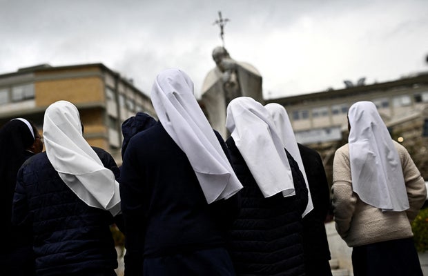 Nuns pray in front of the statue of late Pope John Paul II outside Gemelli Hospital, where Pope Francis continues his treatment, in Rome, Italy, Feb. 25, 2025.