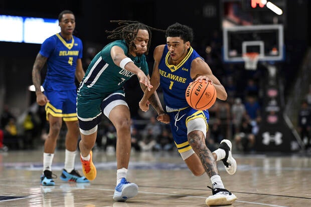 Delaware guard Izaiah Pasha (1) drives to the basket against UNC Wilmington guard Greedy Williams during the first half of an NCAA college basketball game 