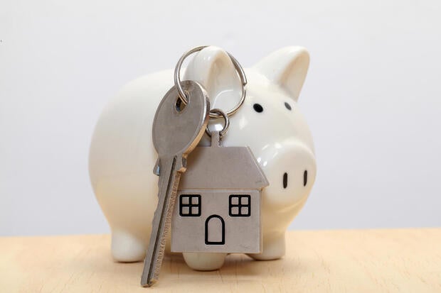 Piggy bank and house key against white background 