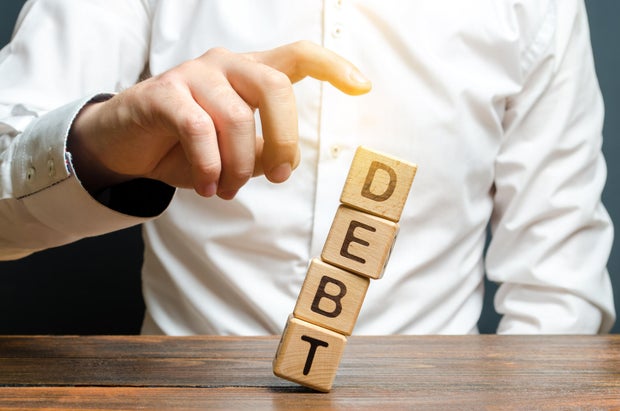 A businessman pushes down a tower of cubes with the word Debt. concept of financial relief, loan restructuring. Financial stability and independence. Reducing domestic and external debt of the state.