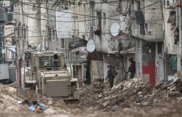 Israeli soldiers stand near a military bulldozer in the center of the Tulkarm refugee camp in the West Bank city of Tulkarm, March 22, 2025. 