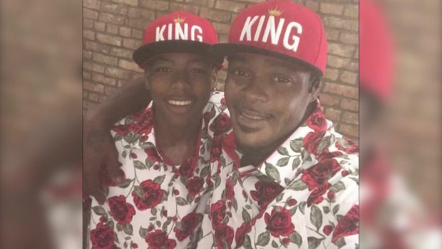 Sincere Jazmin and Miguel Jazmin in matching floral shirts and "KING" baseball hats 