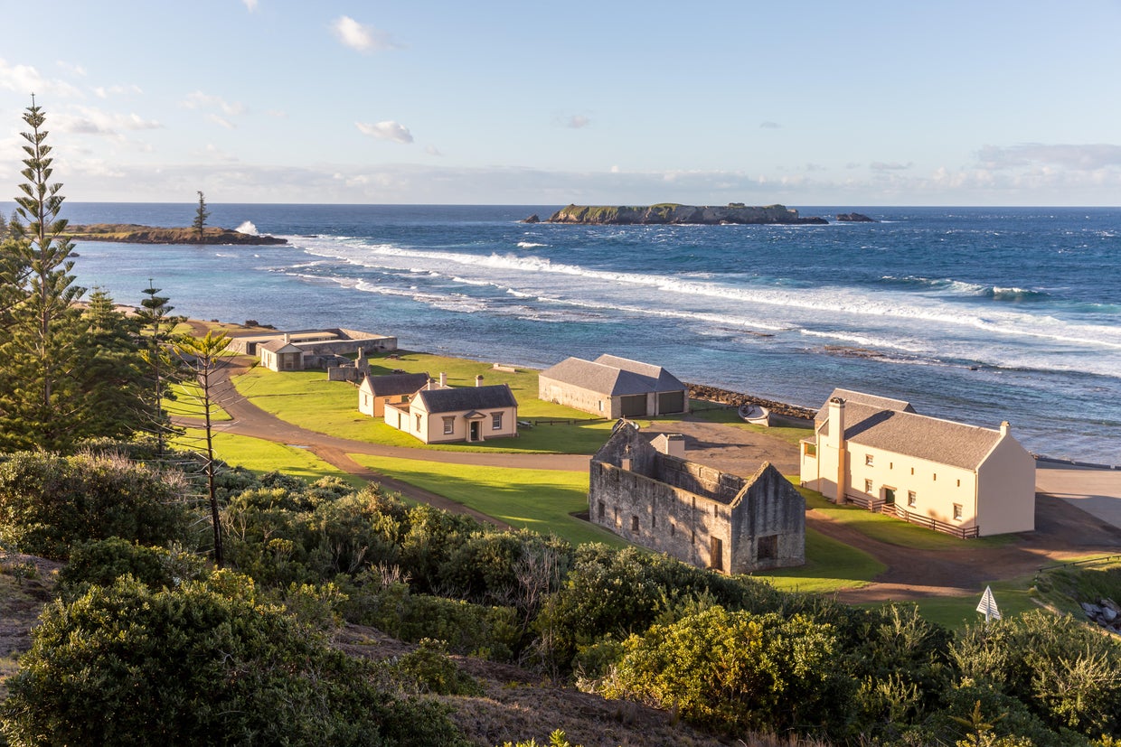 A view of historic buildings on the Australian territory of Norfolk Island, with Emily Bay and Nepean Island visible in the background