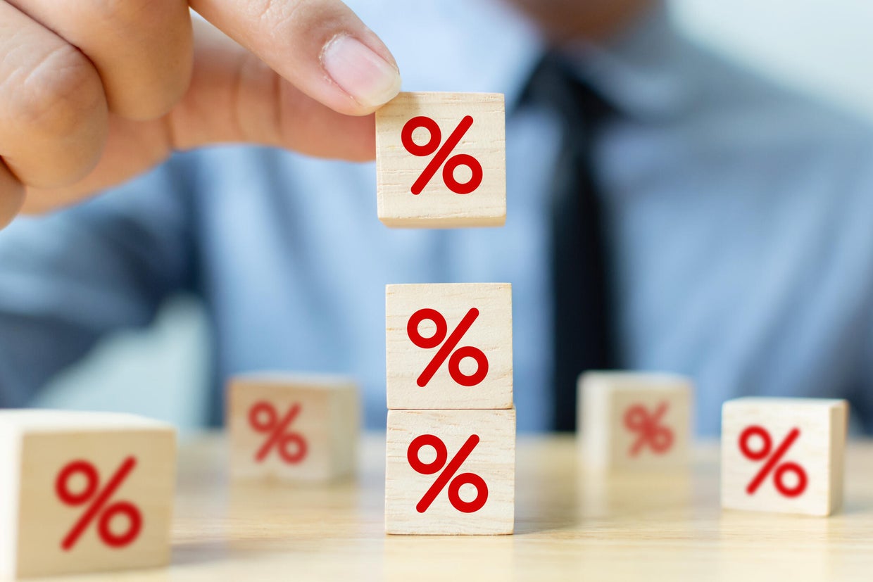 Interest rate financial and mortgage rates concept. Hand putting wood cube block increasing on top with icon percentage symbol upward direction 