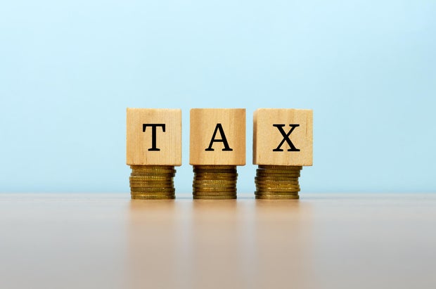Tax text written on wooden block with stacked coins 