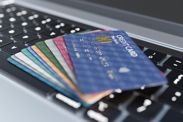 Stack of colorful credit card on a silver laptop. Illustration of the concept of credit card consumerism 