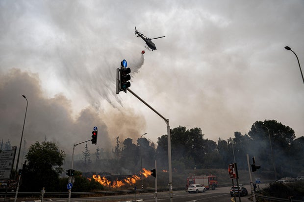 An Israeli firefighting helicopter pours water on flames as a wildfire burns around Jerusalem