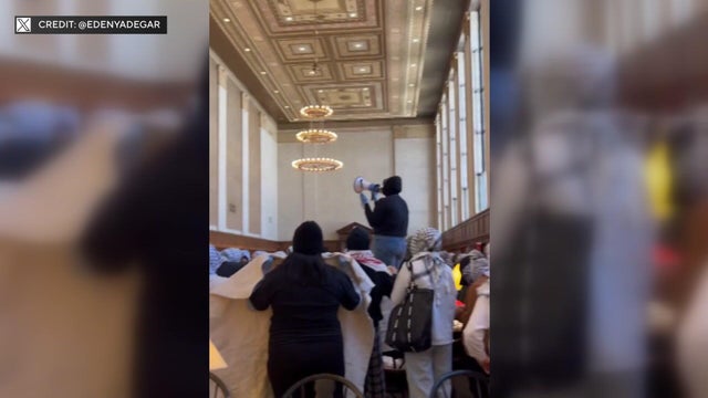 Protesters inside Columbia's library, including one individual with a megaphone. 