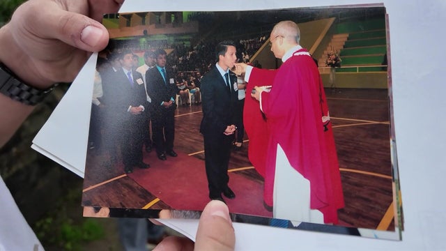 A man holds a photo of Pope Leo XIV and himself at his confirmation years ago. 