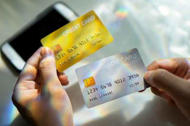 Closeup hand holding blank credit card black, gold, platinum color, spectrum light and shadow background 