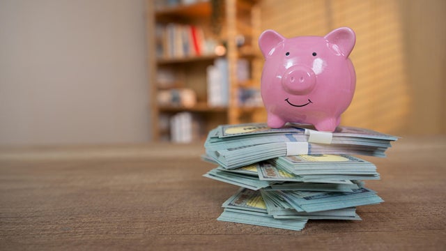 Piggy Bank on top of bundles us paper currency. 