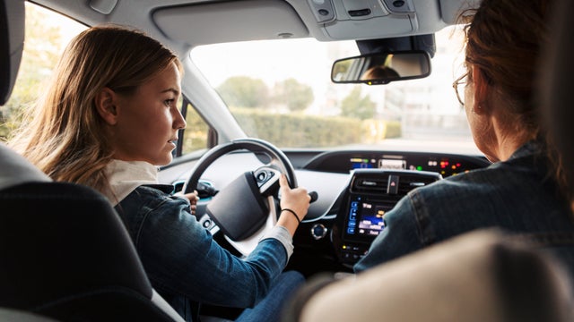 Teenage girl learning to drive from mother during weekend 