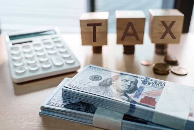 Tax text written on wooden block with stacked coins 