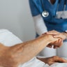 Close-up of caregiver holding senior client hand. Support from nurse to patient, taking care of elderly man in hospital. Emotional support and care in healthcare. 