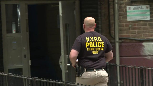 An NYPD officer enters an apartment building. 