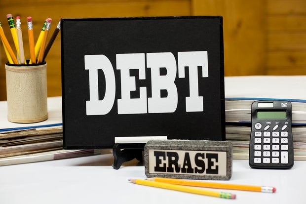Word DEBT on chalkboard with eraser.