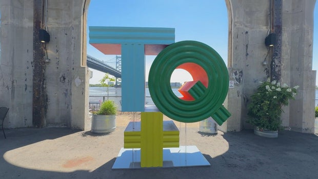 In Plain Sight, a sculpture on Cherry Street Pier, it's a large TQ on top of a plus sign, the T is teal, Q is green, plus is yellow 
