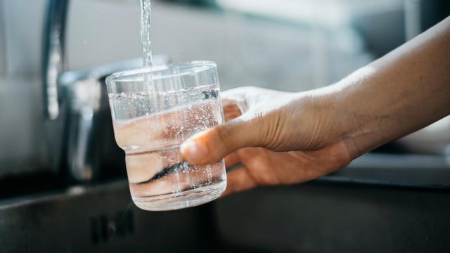 Close up of a woman's hand filling a glass of filtered water right from the tap in the kitchen sink at home 