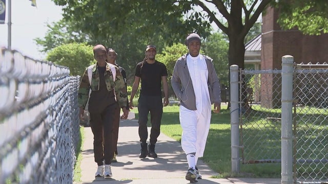 A group of people walk on a sidewalk 