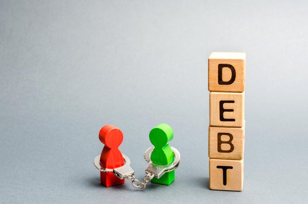 Two people are bound by handcuffs with the word Debt. Creditor and debtor. Financial slavery. Unclosed commitments. Blackmail and illegal pursuit. Psychological pressure. Debts relief. Debt pit.