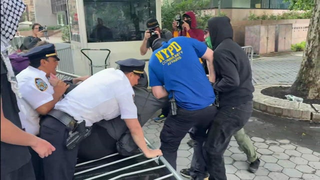 A NYPD officer holds a protester facedown on the ground. 