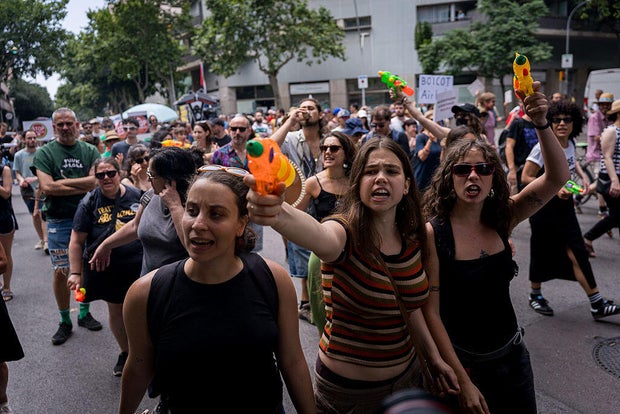 People are seen spraying tourists and buildings with water