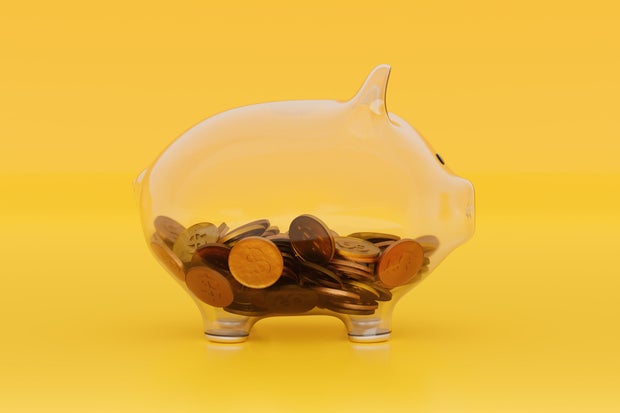 See Through Transparent Glass Piggy Bank With Coins on Blue Yellow 