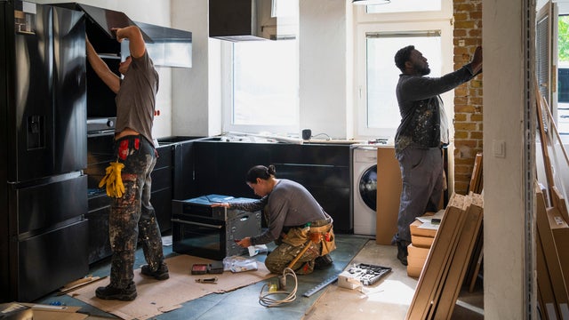 Diverse male and female carpenters working in kitchen at site 