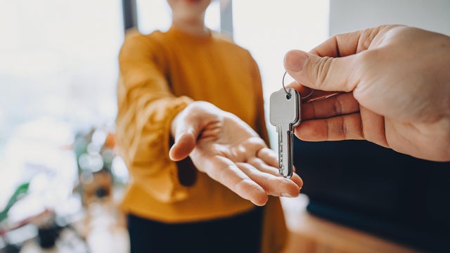 Close-up shot of a real estate agent giving a young Asian woman the keys to her new home. Home ownerships concepts 