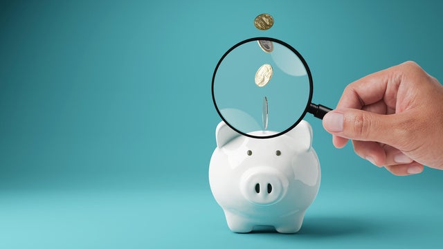 Piggy bank with magnifying glass. Money box with falling coins. moneybox investing, 3D rendering 