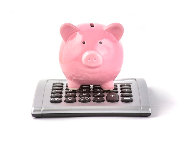 Pink piggy bank sits on the calculator on white background 