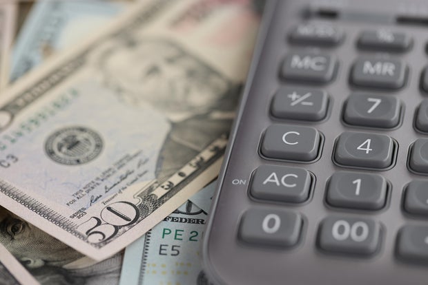 Gray calculator lying on dollar bills closeup 