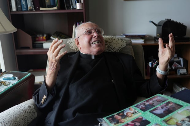 100-Year-Old Priest laughs during an interview in his apartment 