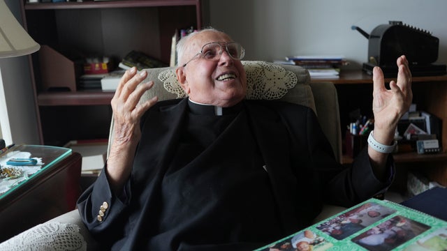 100-Year-Old Priest laughs during an interview in his apartment 