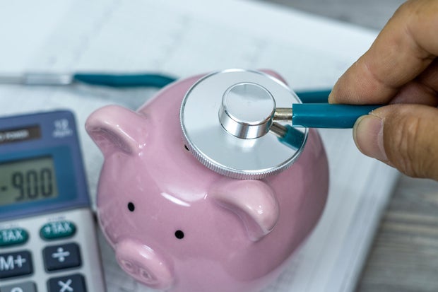 Financial health check on debt or loan concept, saving pink piggy bank with stethoscope. 