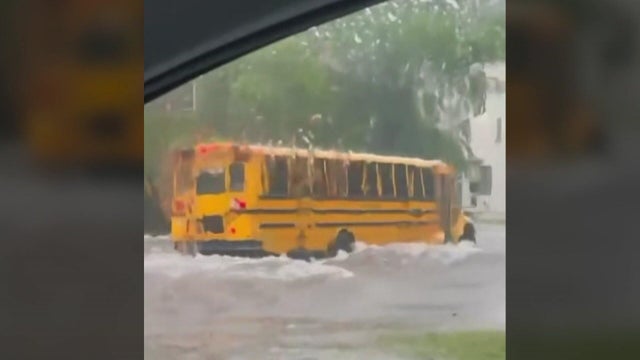A school bus drives through high flood waters 