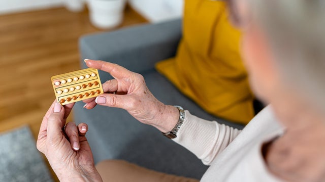 A close-up photo of a woman using pills for controlling hormones during menopause. 