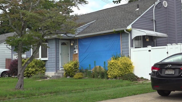 A home with a large part of the wall covered with a blue tarp. 