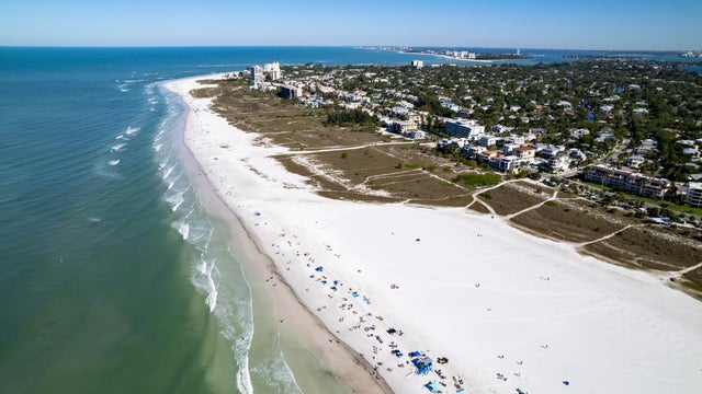 Aerial view of calm bay, beach and community 