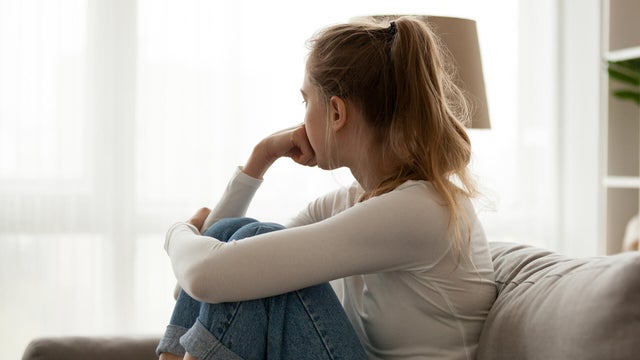 Upset woman sitting on couch alone at home 